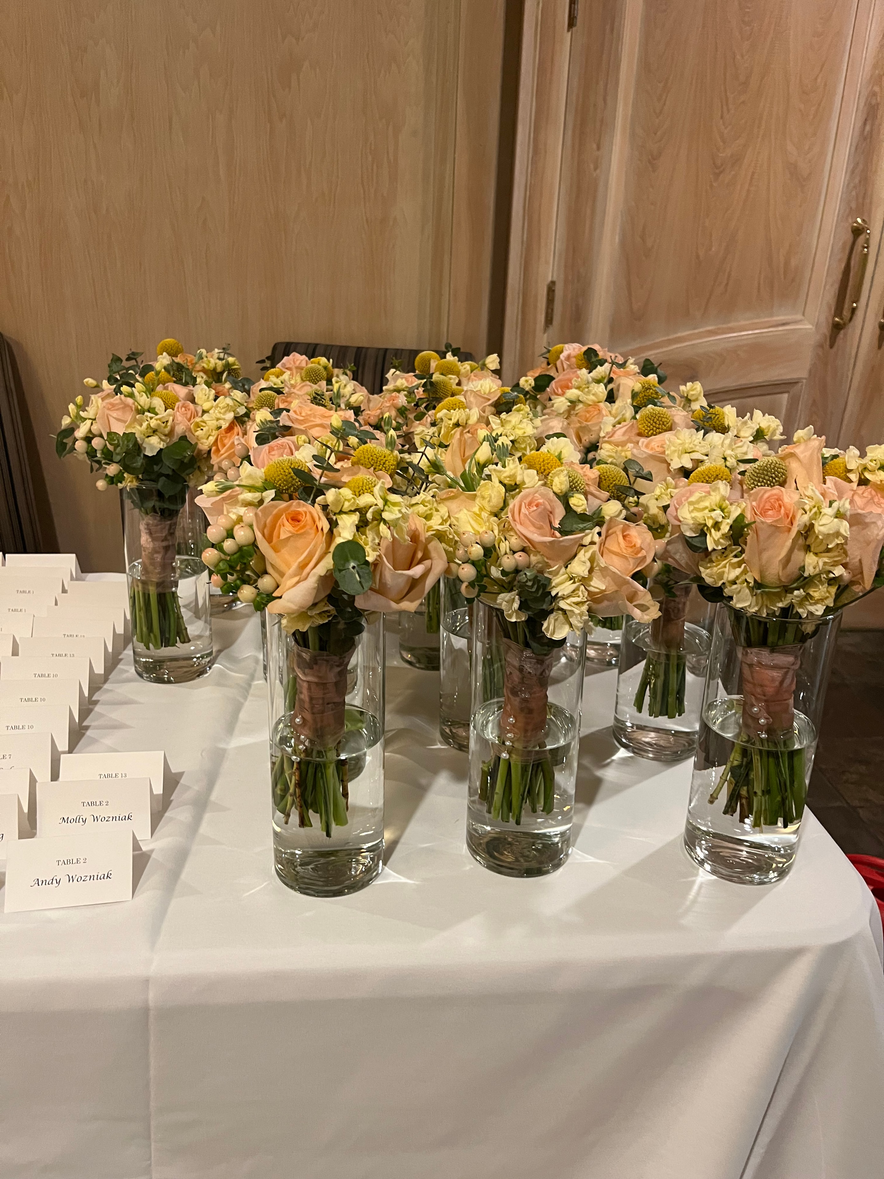 Peach roses and yellow button mums garland with glass cylinder vases on banquet table with place cards