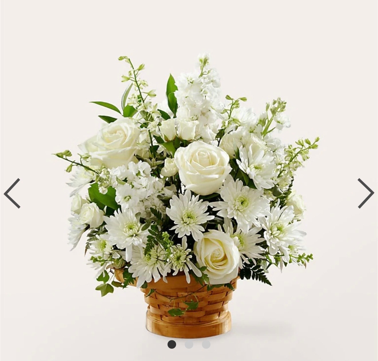 White roses and chrysanthemums with greenery in wicker basket