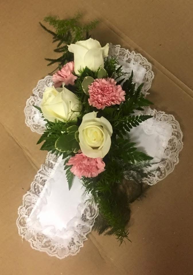 White roses and pink carnations cross pillow arrangement with lace trim
