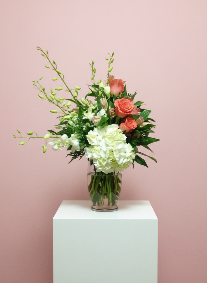 White hydrangeas and coral roses in a glass vase