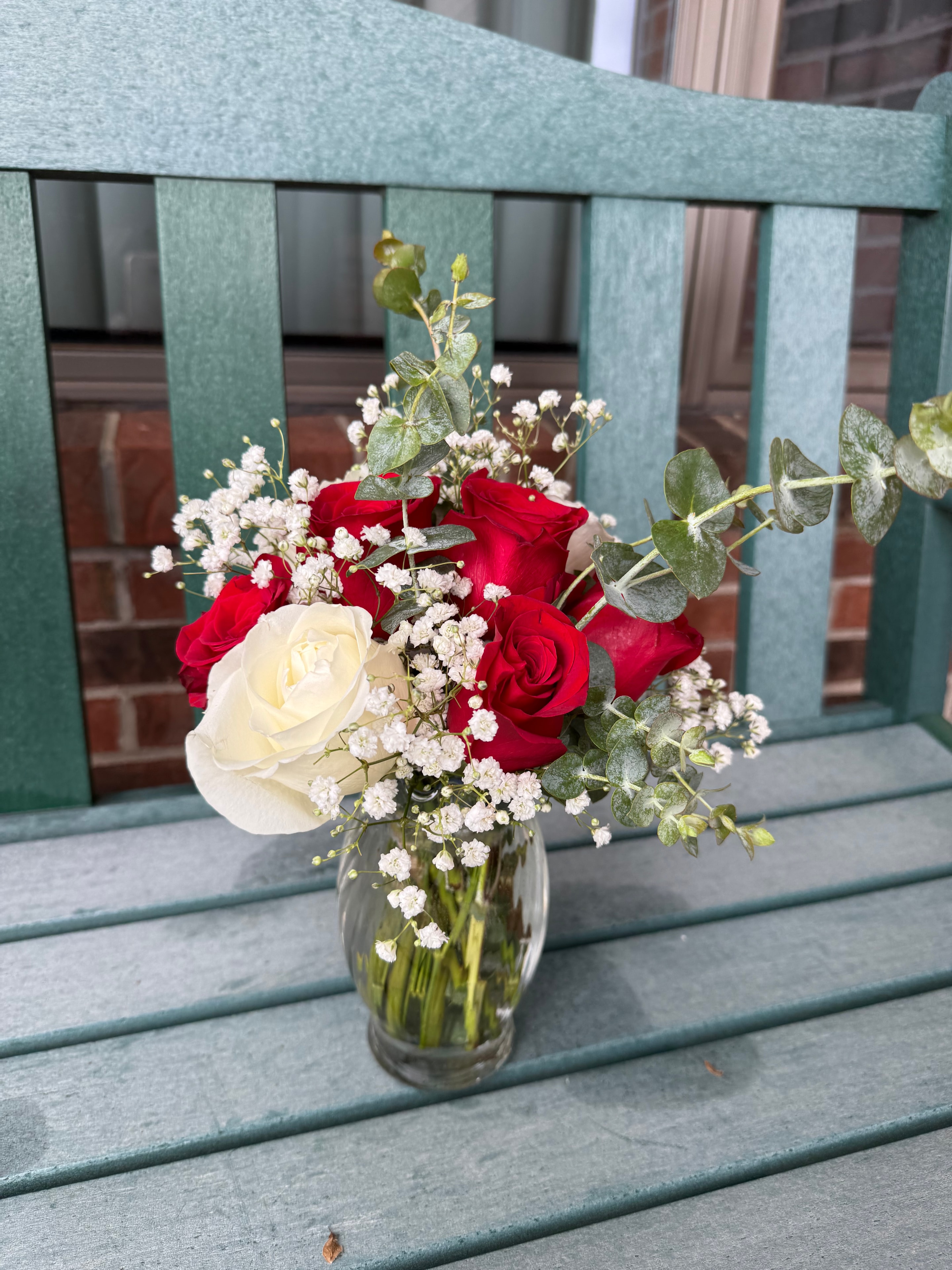Red roses, white roses, and baby's breath in a glass vase