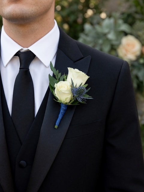 White rose boutonniere with blue thistle on blue ribbon