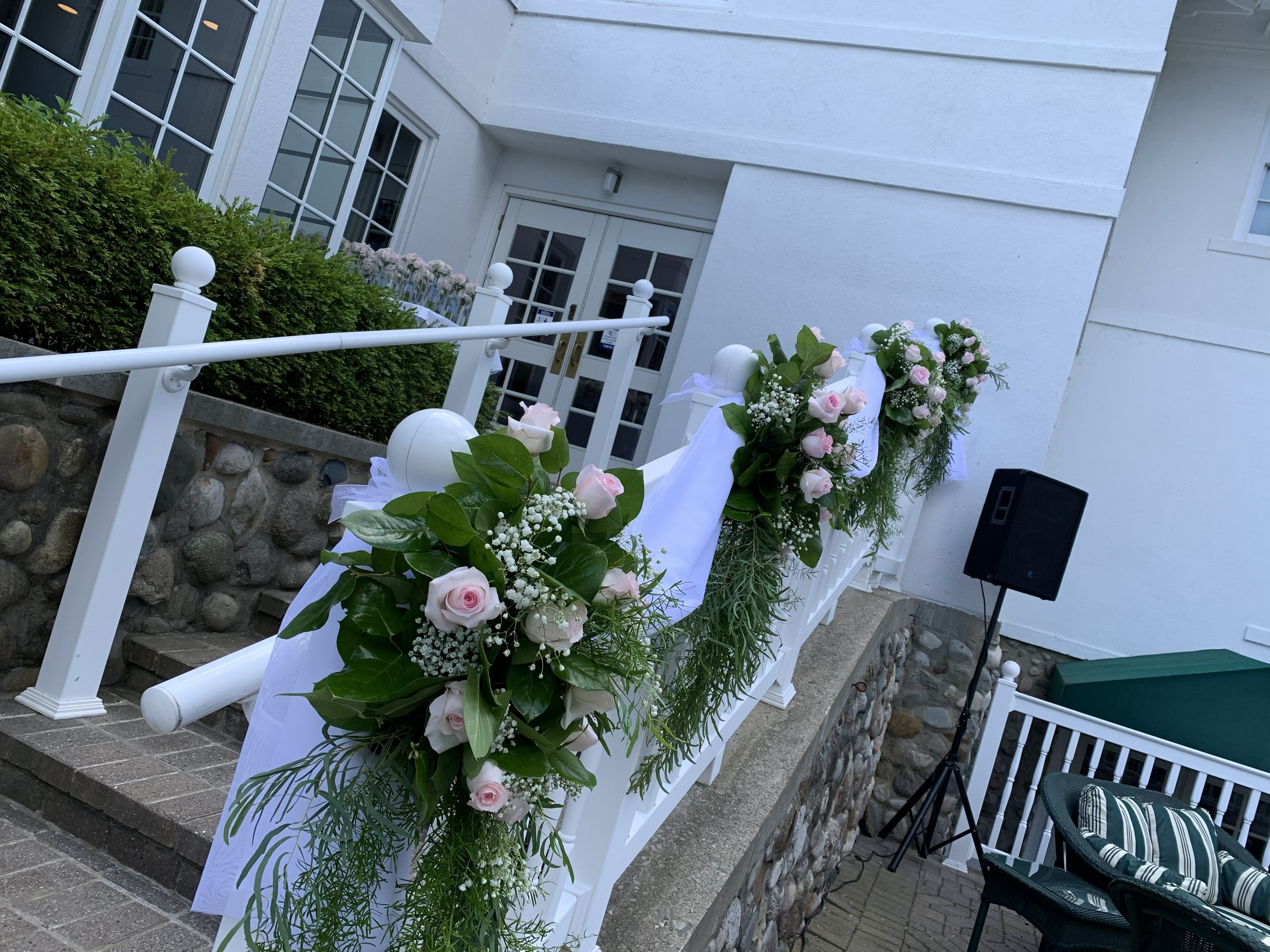 Pink rose and baby's breath staircase railing décor at outdoor venue