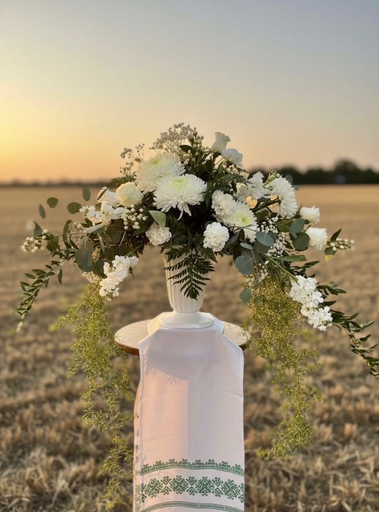 White carnation and greenery arrangement in decorative vase
